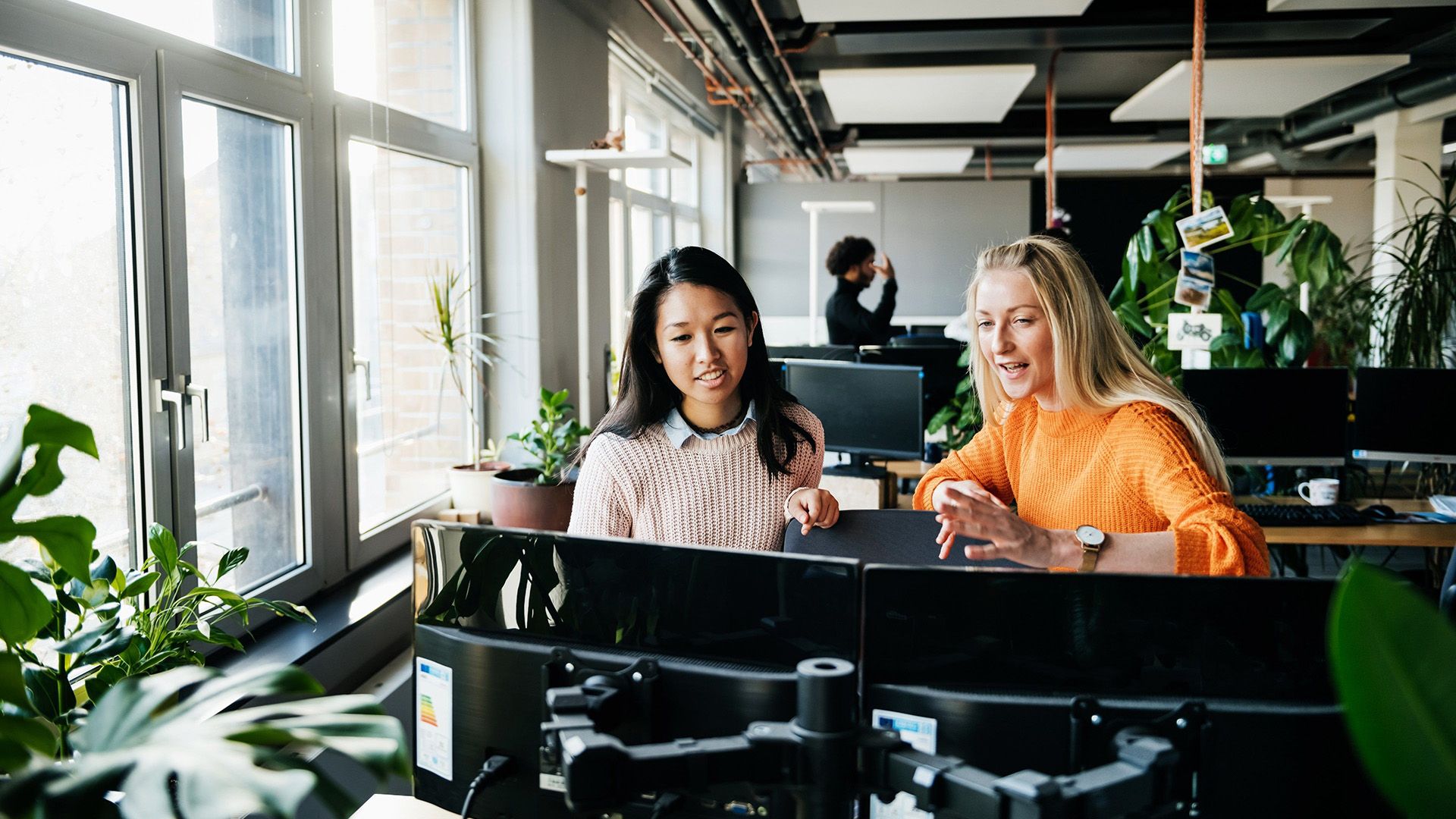 Two people discuss their creative AI workflow in an open plan office space.