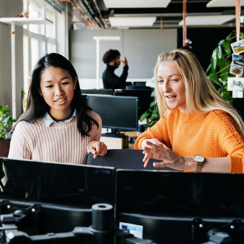 Two people discuss their creative AI workflow in an open plan office space.