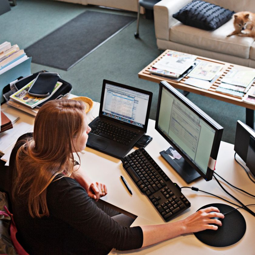 A person at a desk with a laptop and a monitor, considering whether to back up their files to cloud storage.