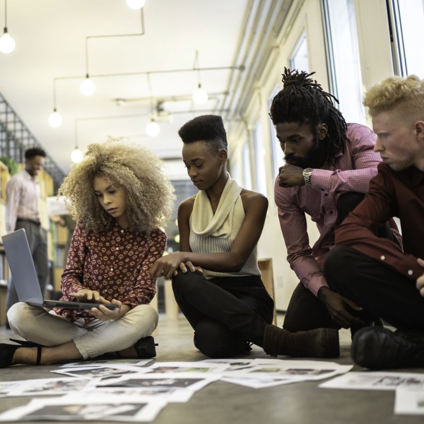 Group of people reviewing photographs on the floor in an office space.