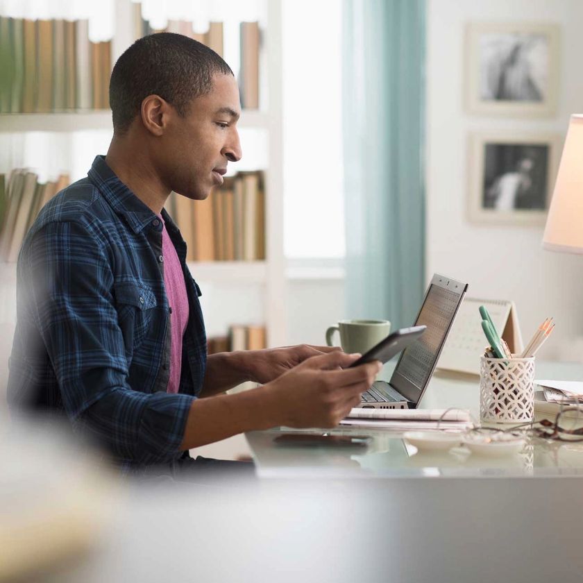 A professional works on a laptop and a mobile device as they back up their files to the cloud.