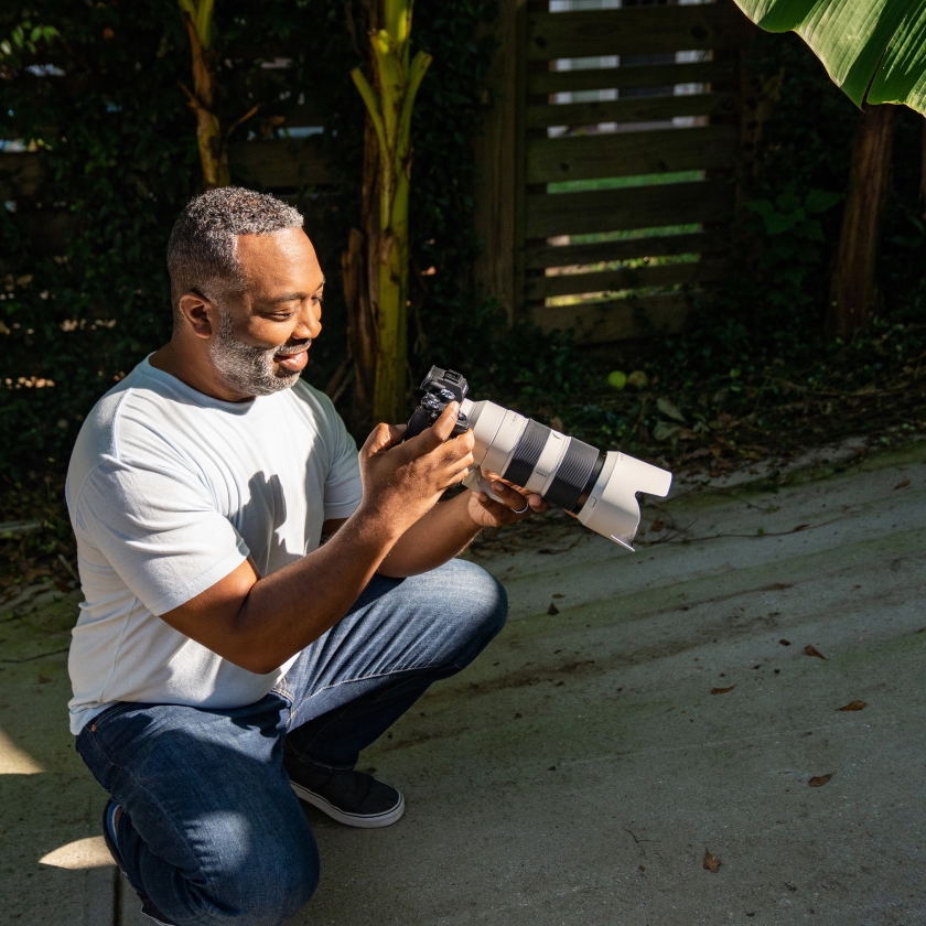 A photographer reviews photos on a DSLR camera before uploading them to cloud storage.