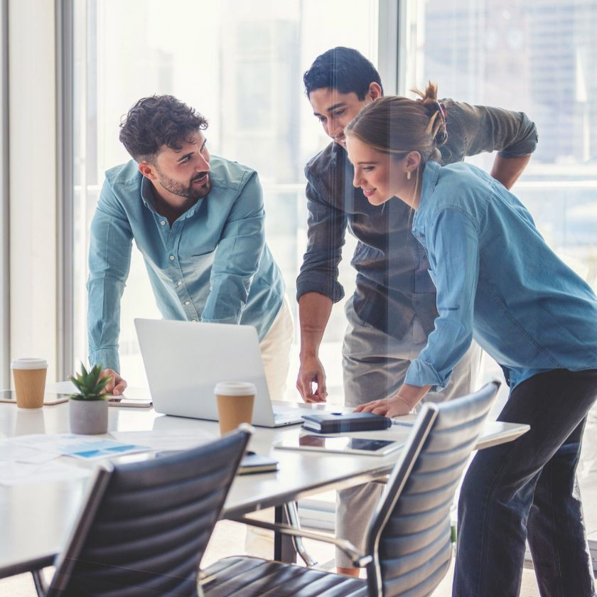 A sales team collaborates around a laptop.