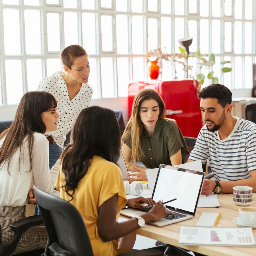 Colleagues working together around a desk in an office.
