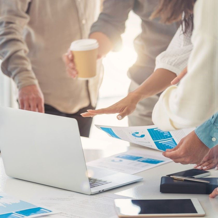 A group of people gather around a table while discussing document analytics.