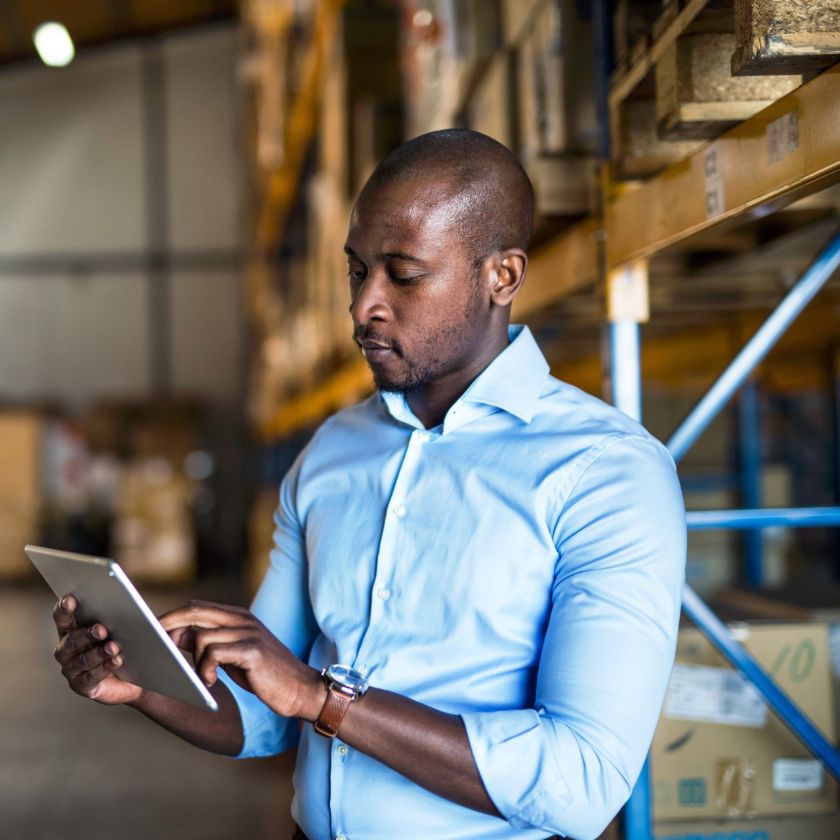Person in a warehouse using a tablet to add an eSignature to a document as part of efforts to improve operational efficiency.
