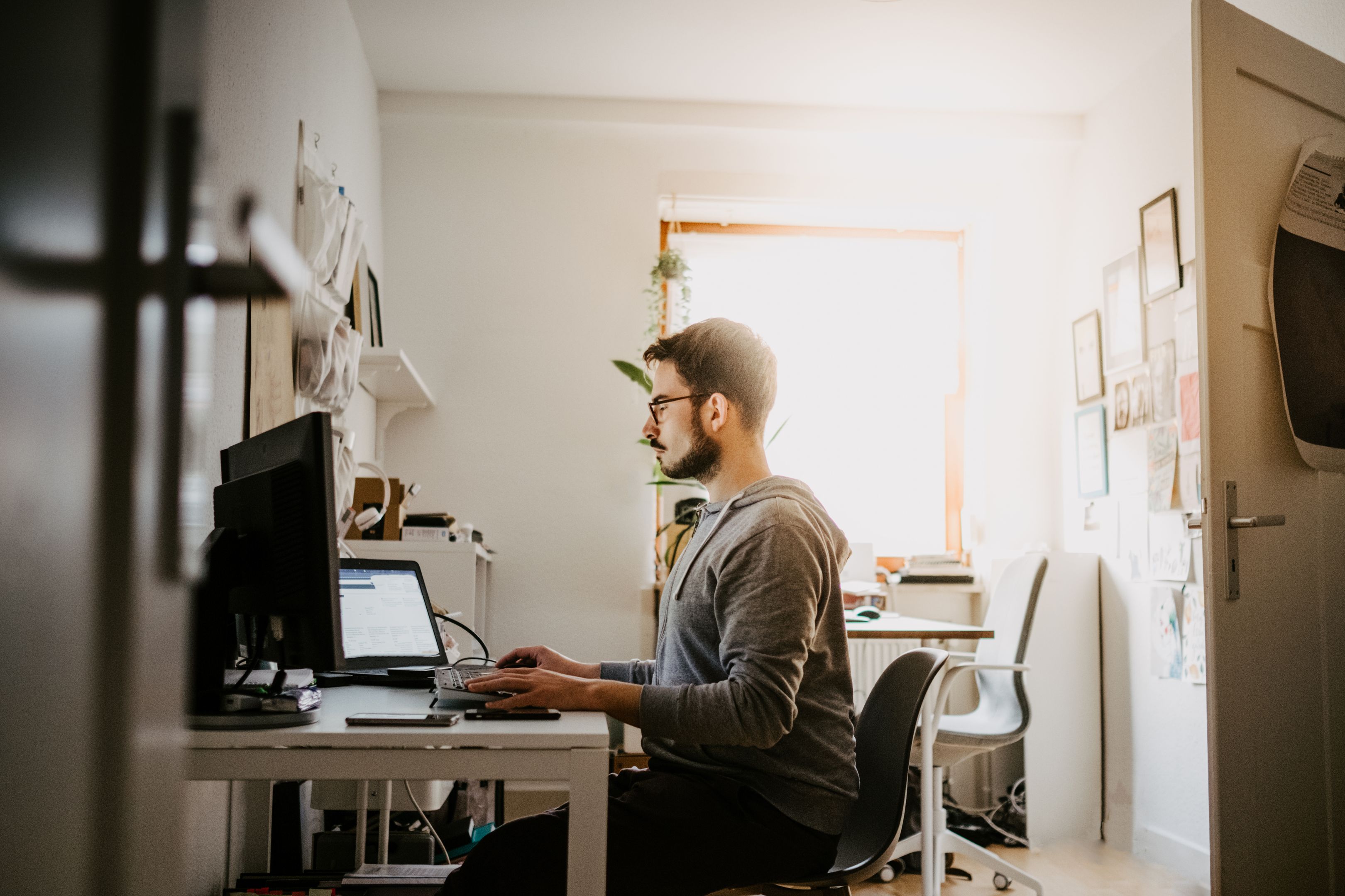 A man sits at a desk in a home office while sharing files via the cloud.