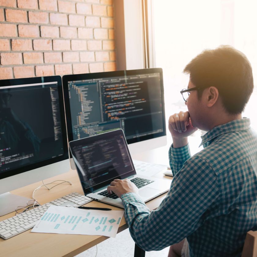 A person sits at their computer desk while contemplating how to backup computer files to an external drive.
