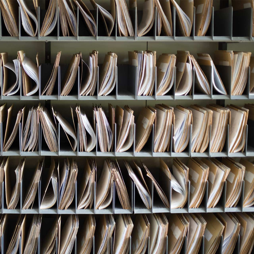 A shelving unit with five shelves, each one full with organized files and documents.