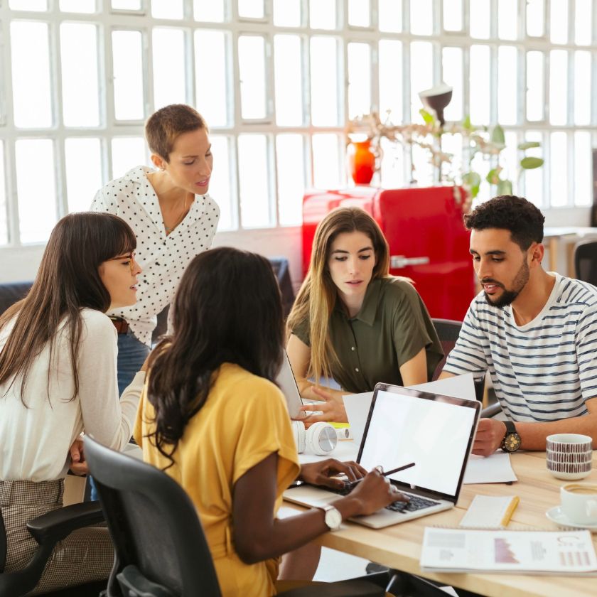 A team of people work together around a table in an office.