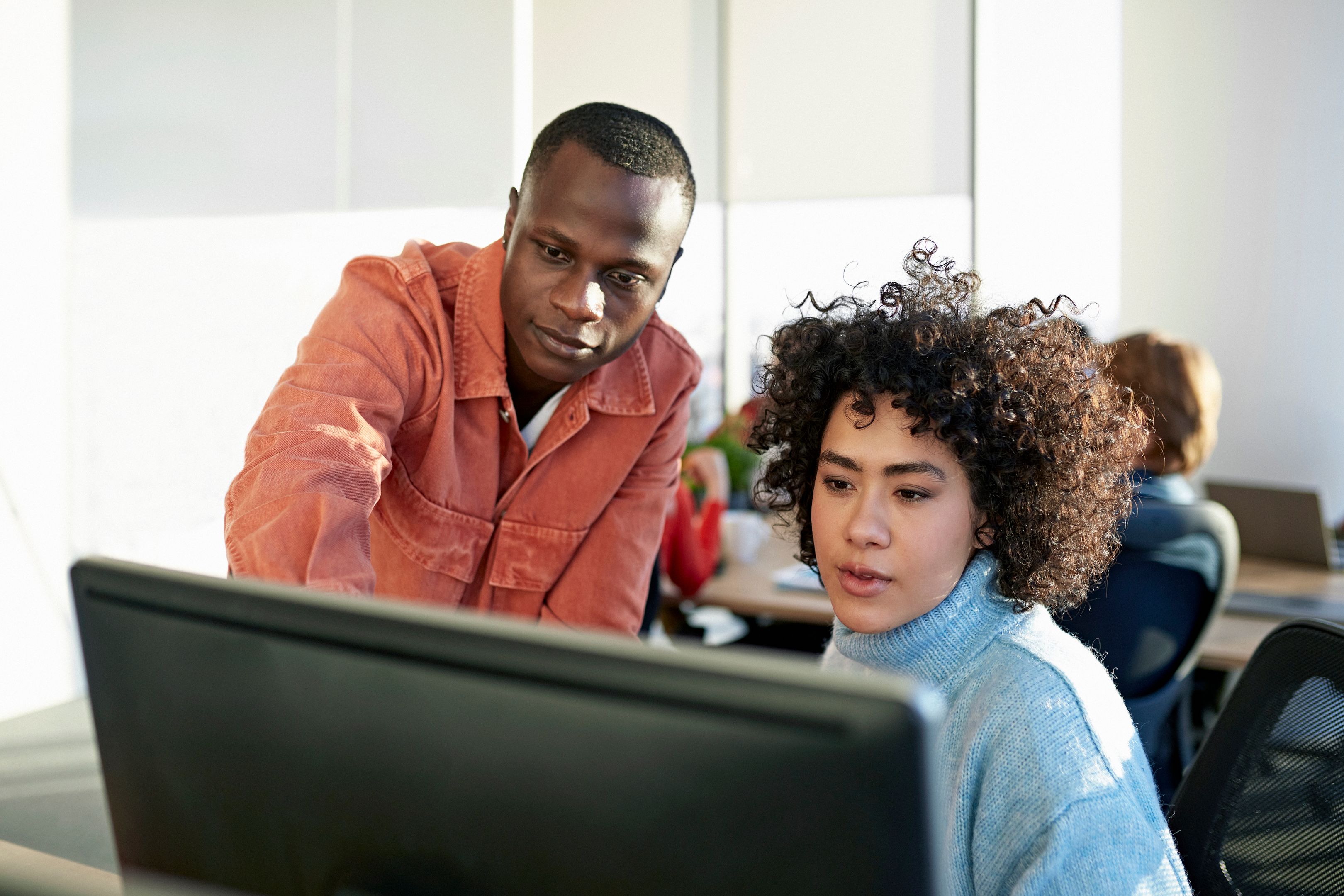 Two people look at a desktop screen together, capturing hands-on collaboration for setting up cloud data security.