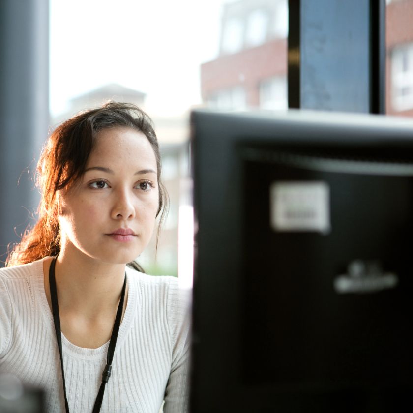 A person in an office looks at their computer screen, looking up ways to combat burnout.