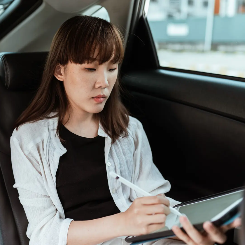 A person sat in a car signs a PDF on their tablet with an eSignature.