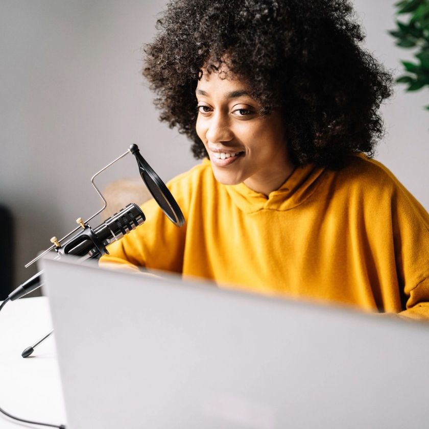 A podcaster talks into a microphone while recording an episode.