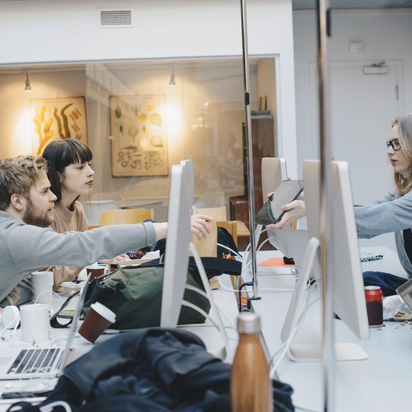 A professional shows a tablet device to their colleagues in an office.