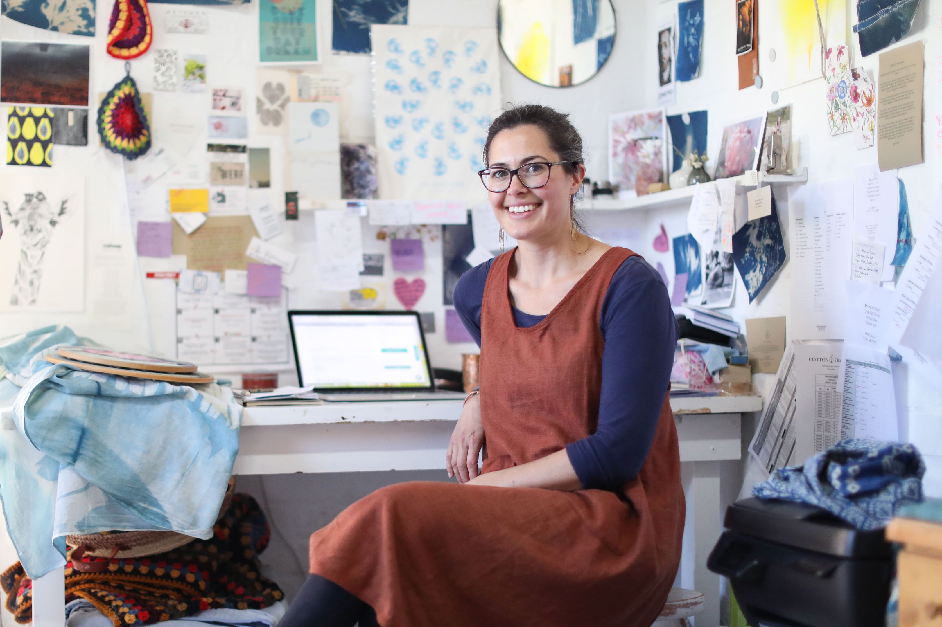 Person in a creative workspace, surrounded by projects and a laptop, illustrating the need to send large files efficiently. 