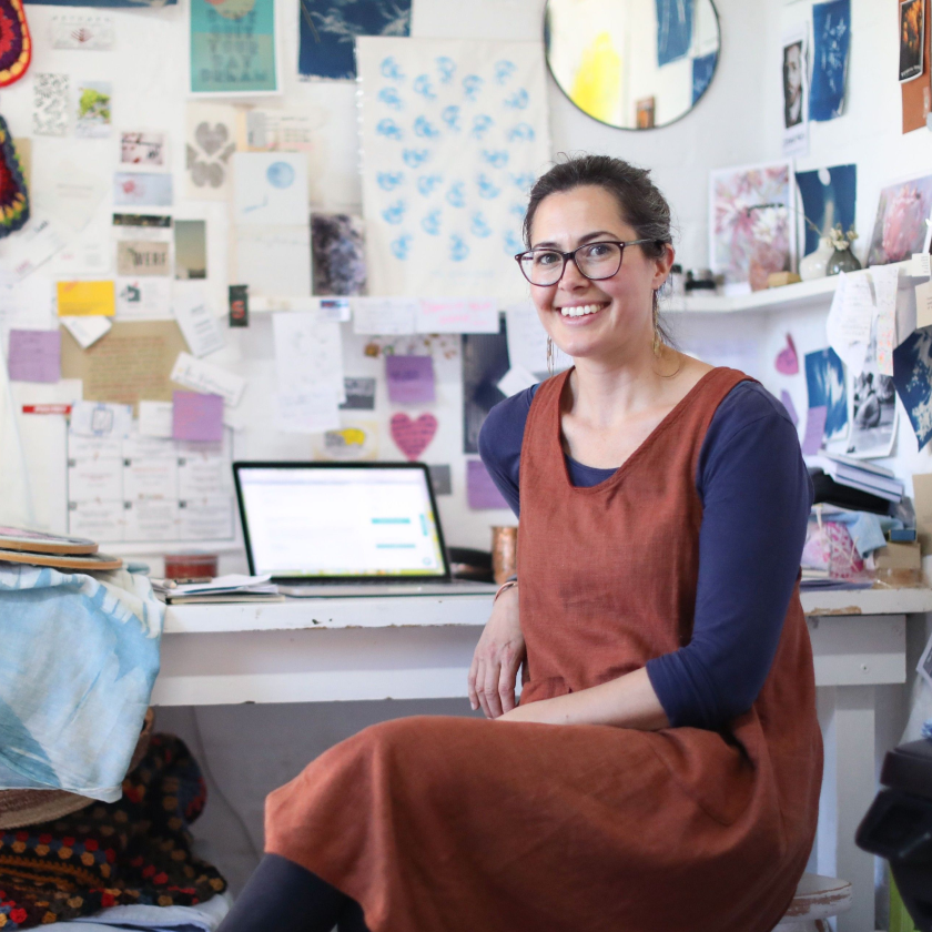 Person sitting at a desk surrounded by projects and a laptop, seeking a way to easily send large files.