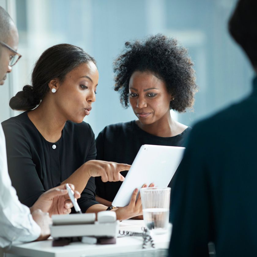 A group of people gather around a busy meeting table discussing some important business.