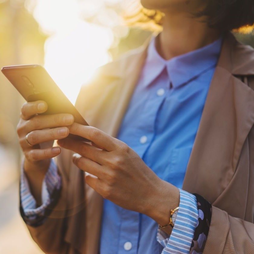 A person stands outside while using Dropbox on their phone.