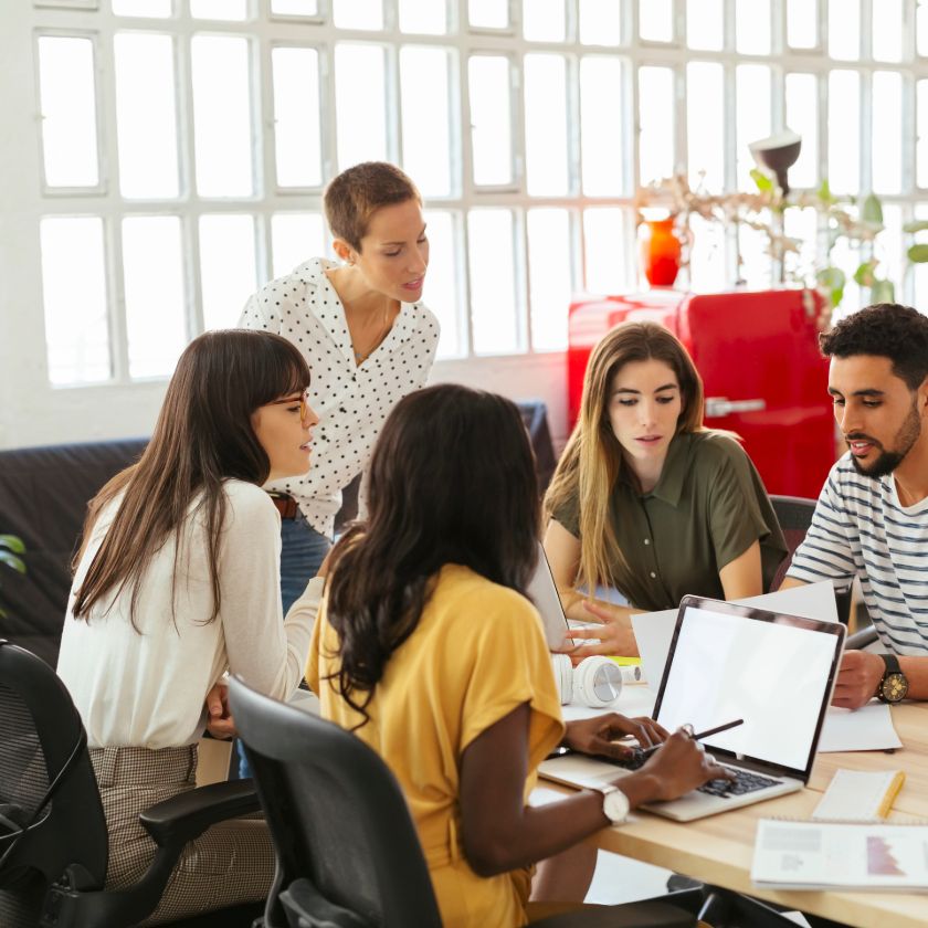 A marketing manager holds a discussion at an office meeting table.