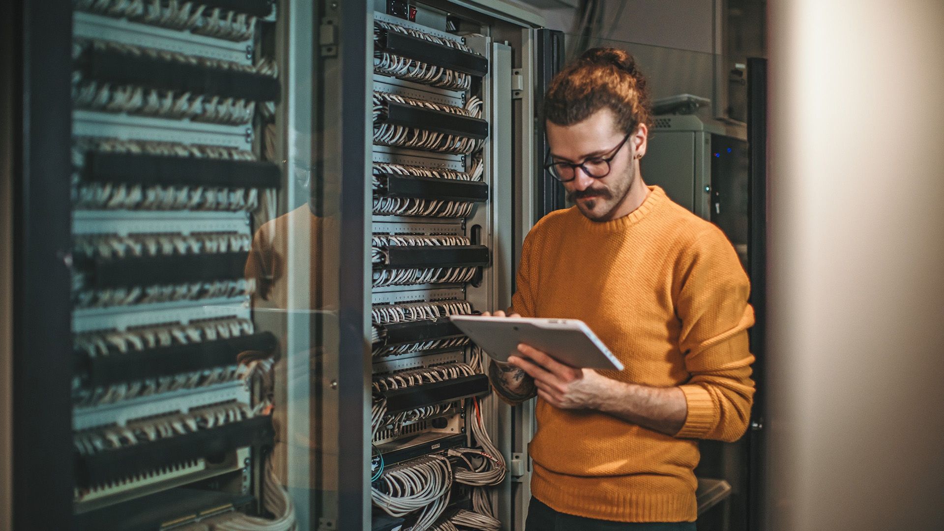 An engineer examines some important hardware in a server room.