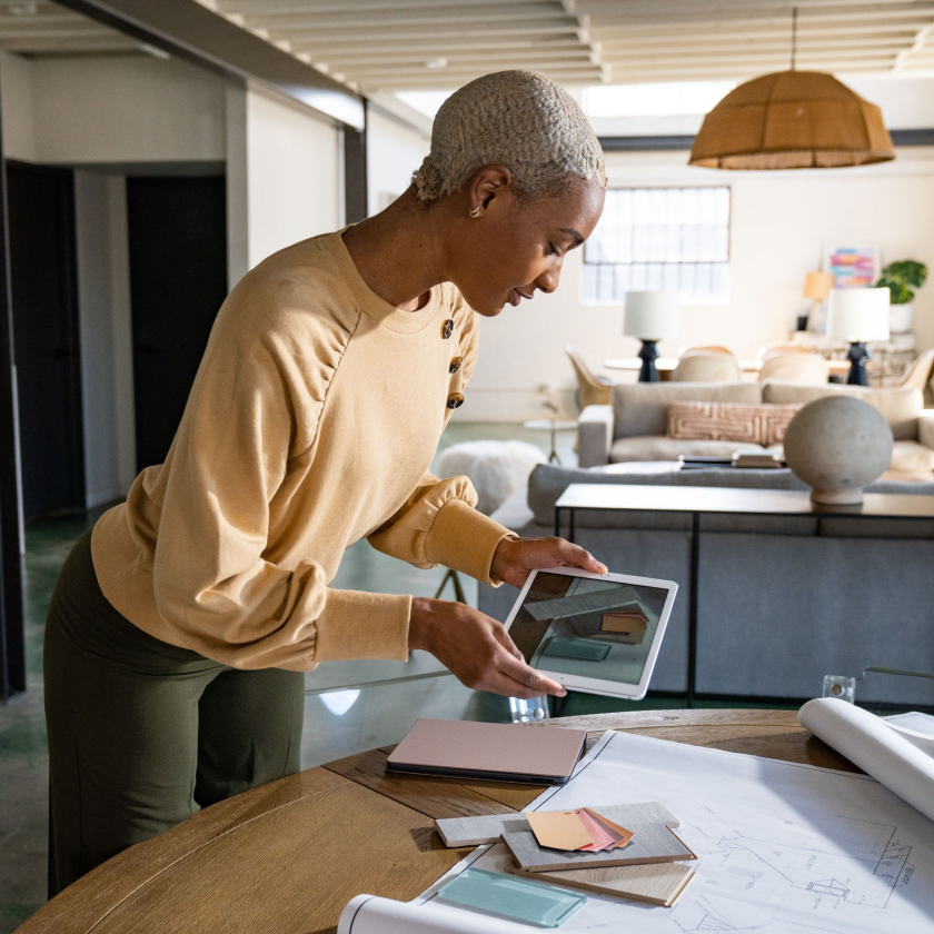Person reviewing a tablet while working on design plans, representing sharing large files with clients