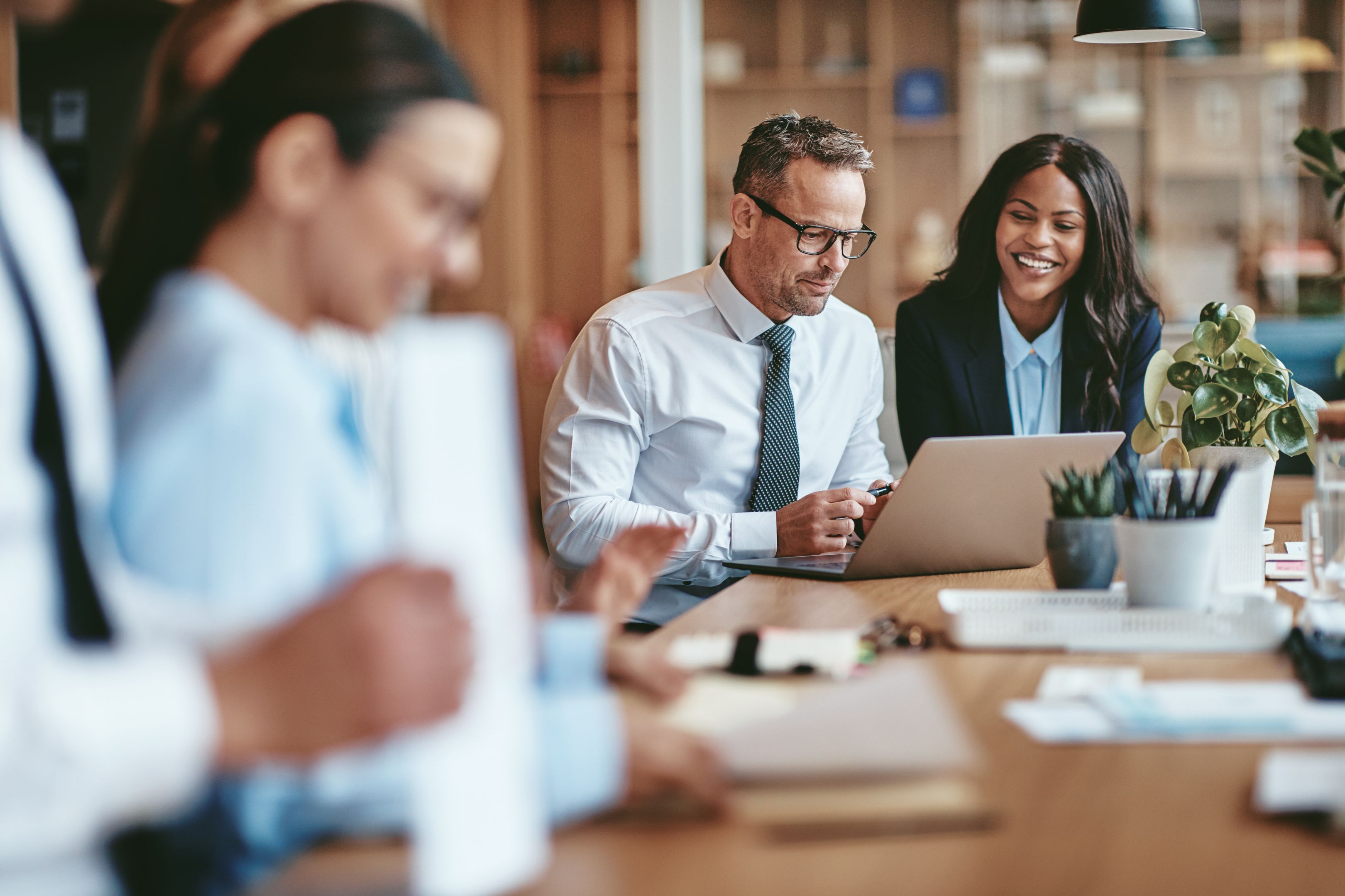 Two workers sat side-by-side, smiling and working together to symbolis teamwork and building trust in distributed teams