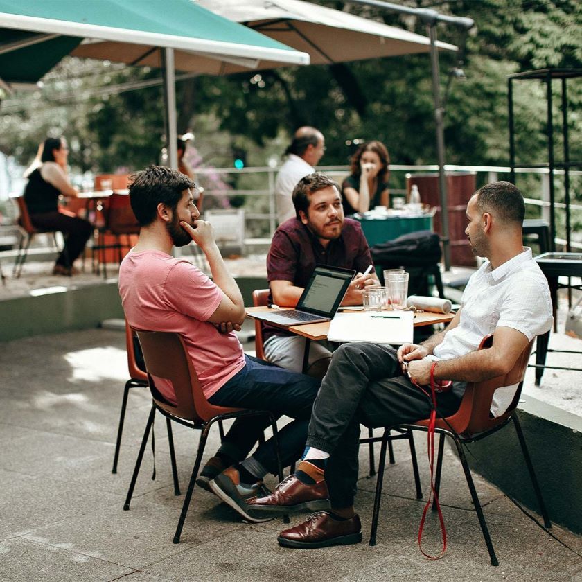 Three colleagues collaborate in a relaxed environment at a café.