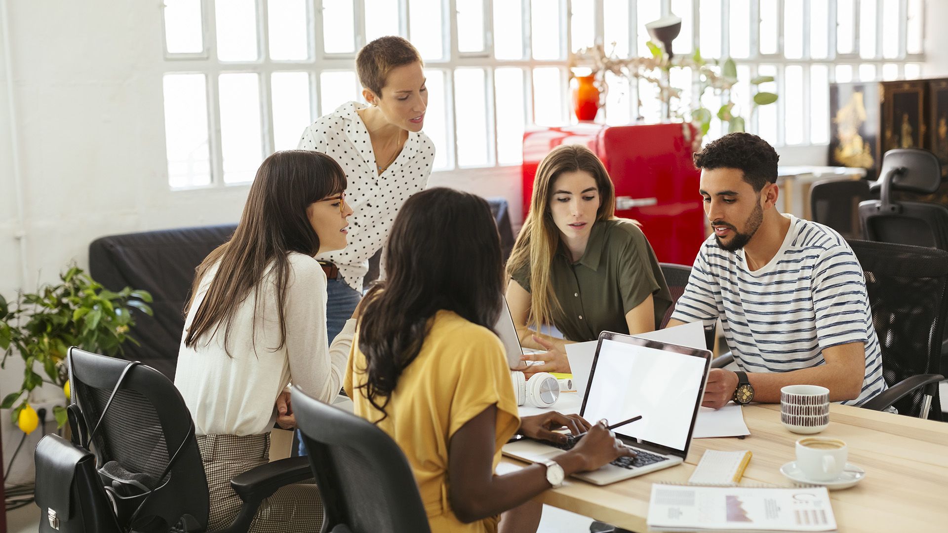 A group of people gather at a meeting table and discuss their social ad creative.