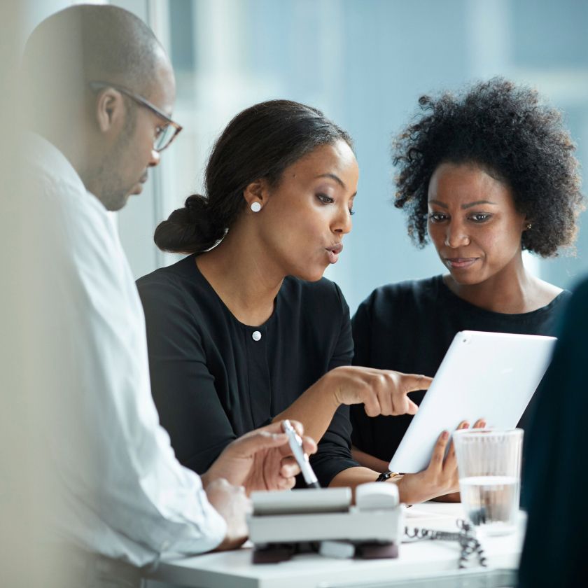 A group discusses their sales prospects while sitting at a meeting room table.