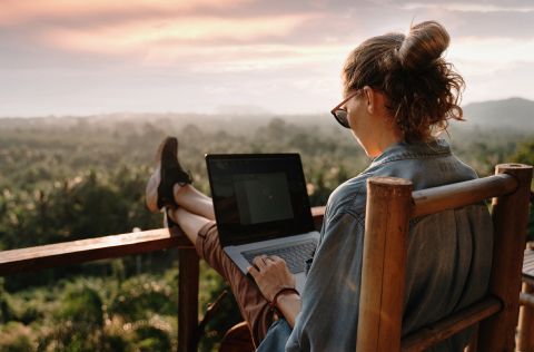 A solopreneur takes a moment to relax on a balcony with their laptop.