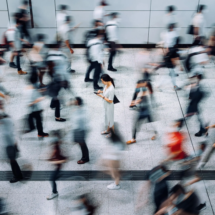 A person stops in a busy crowd to check an alert on their phone.