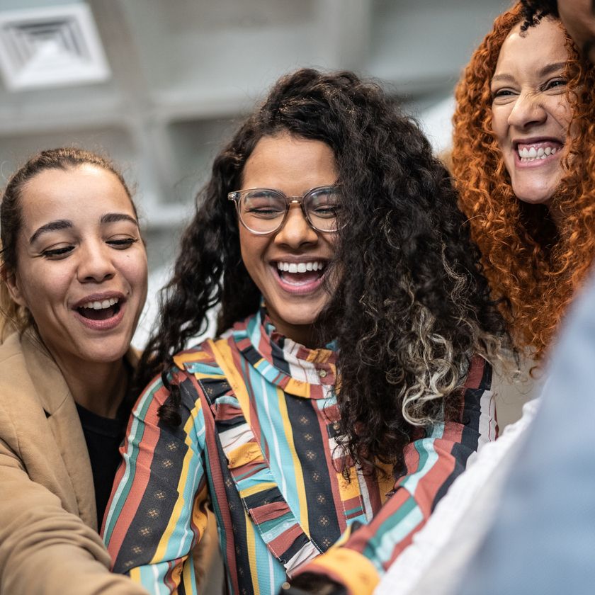 A group of people assembled in a team huddle, smiling and Joyful.