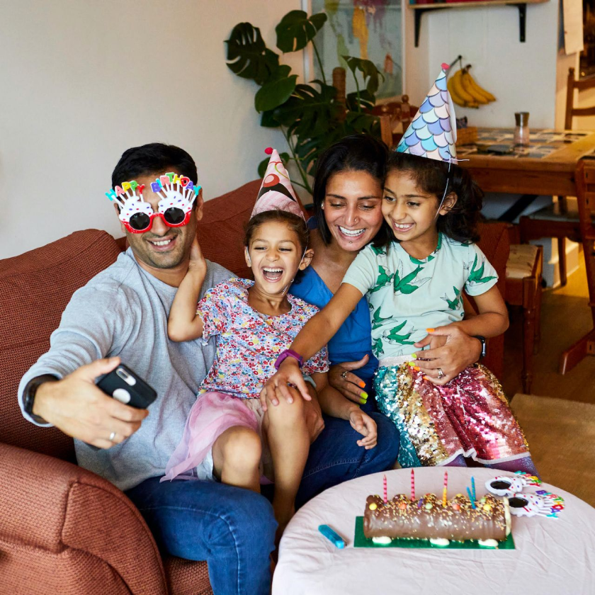 A family of four take a selfie while celebrating a birthday party.
