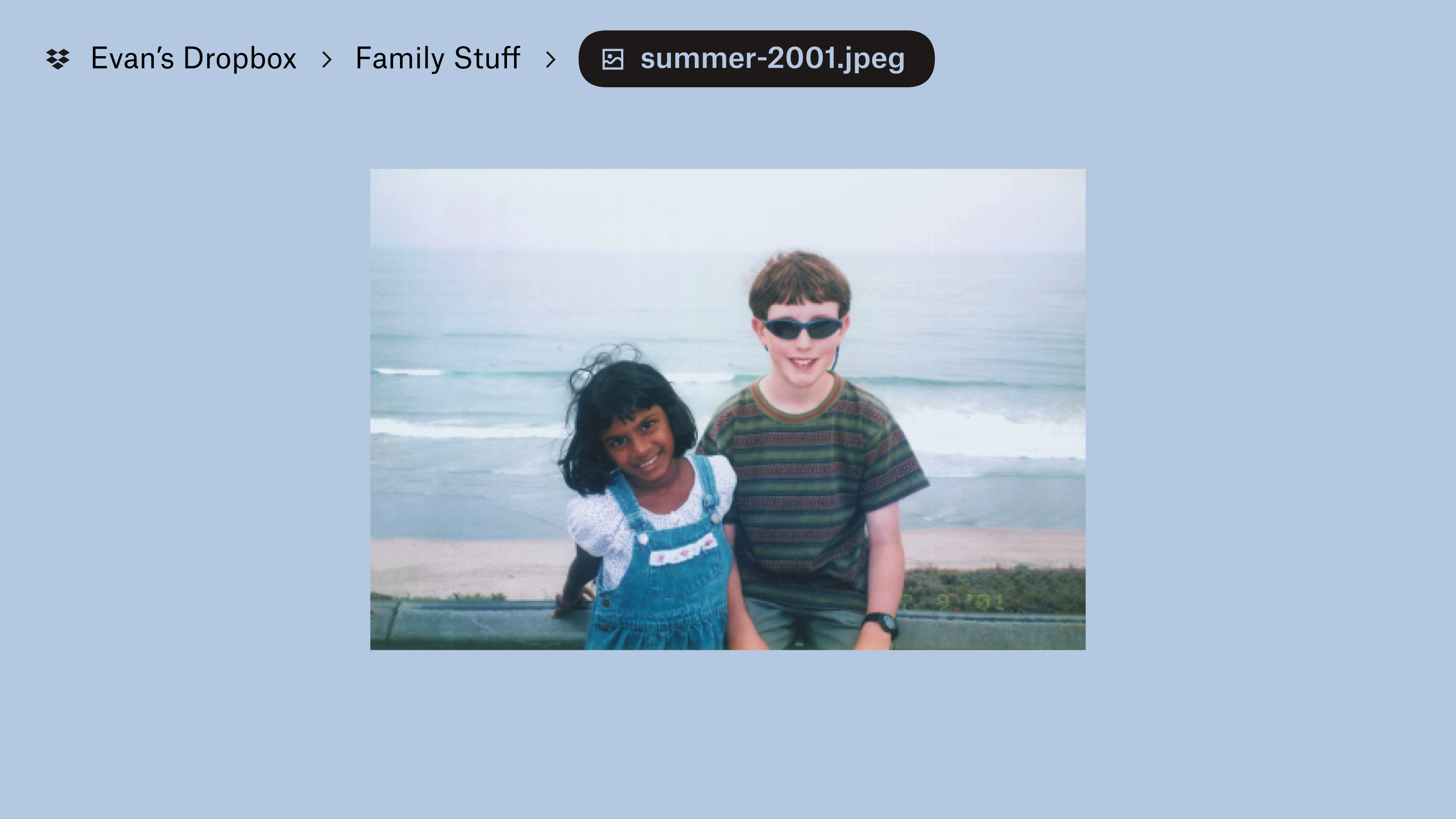 A photo stored in “Evan’s Dropbox” in a “Family Stuff” folder. Two kids smile at the camera, waves on a beach behind them.