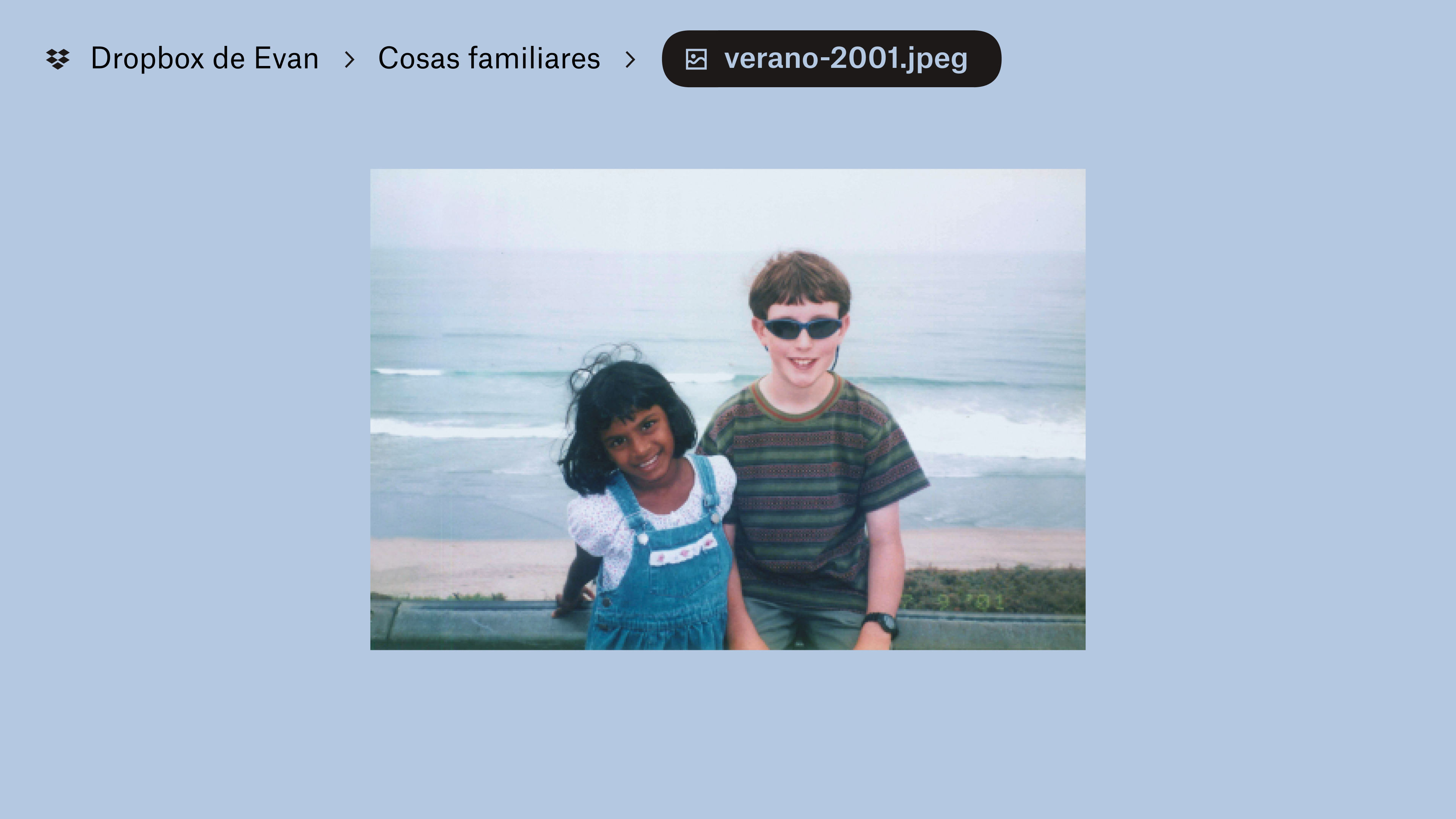 Una foto almacenada en &quot;Evan’s Dropbox&quot; en una carpeta denominada &quot;Family Stuff&quot;. Una niña y un niño sonríen a la cámara, con las olas de una playa a sus espaldas.