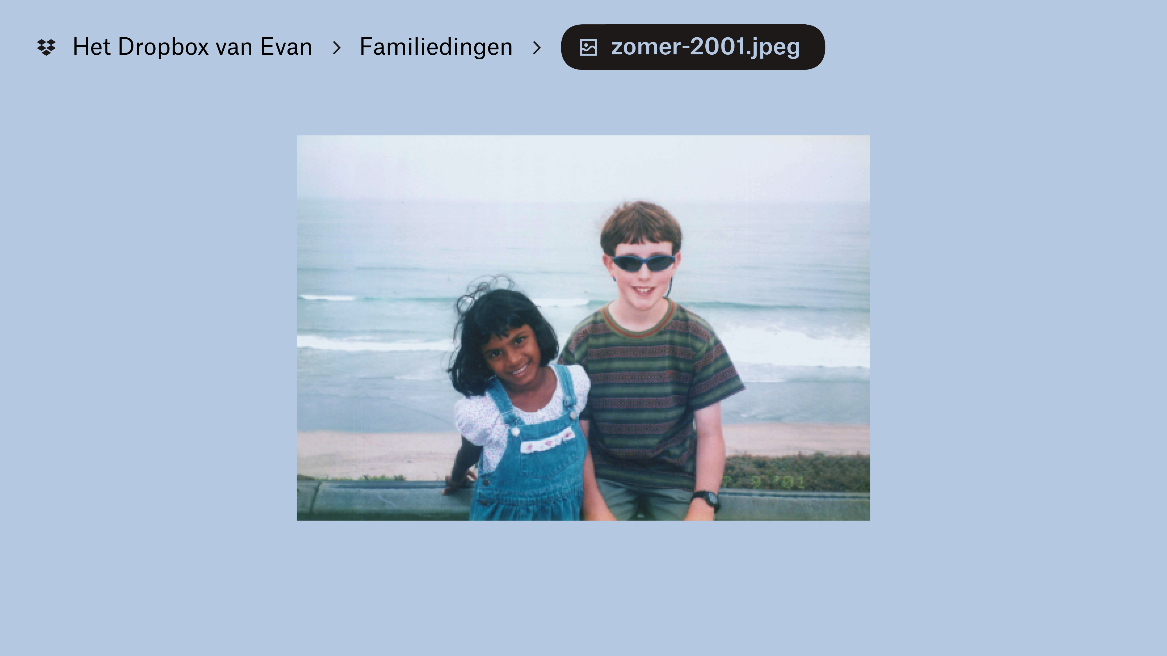 Een foto die is opgeslagen in &quot;Evan's Dropbox&quot; in de map &quot;Family Stuff&quot;. Twee kinderen lachen naar de camera, met golven en het strand op de achtergrond.