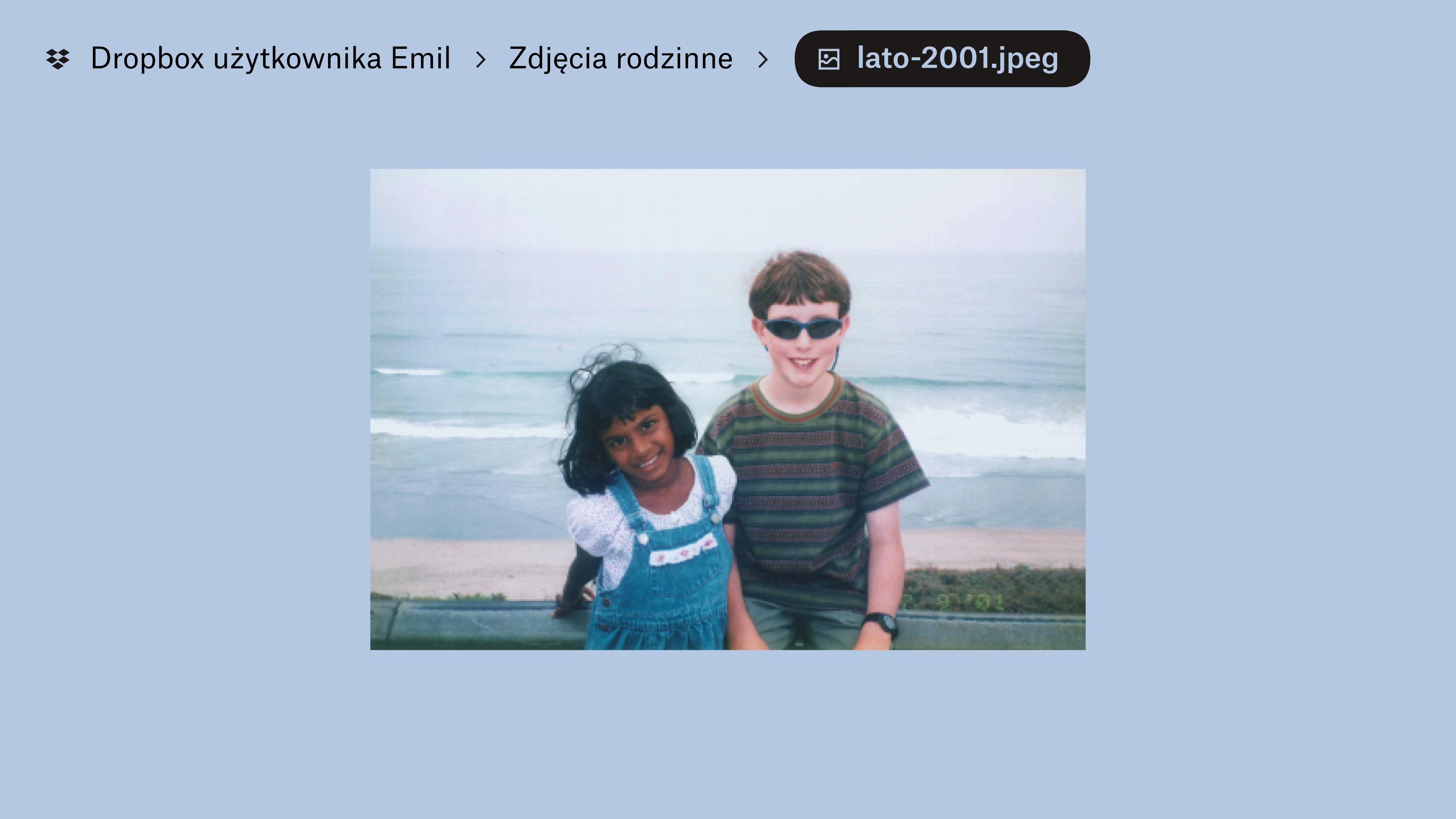 Zdjęcia zapisane w „Dropboxie Evana” w folderze „Spotkania rodzinne”. Dwoje dzieci uśmiecha się do kamery, za nimi widać fale na plaży.