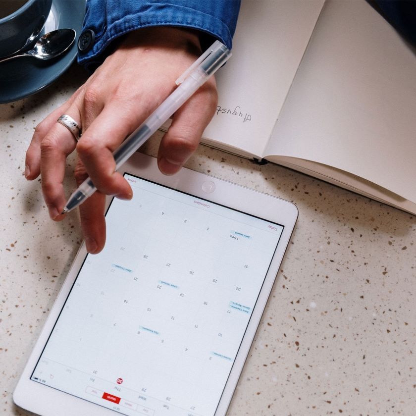 A person adding events to their digital calendar to manage their time.