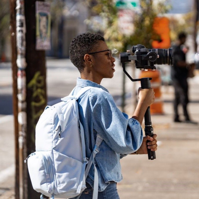 A filmmaker holds a video camera on a gimbal.