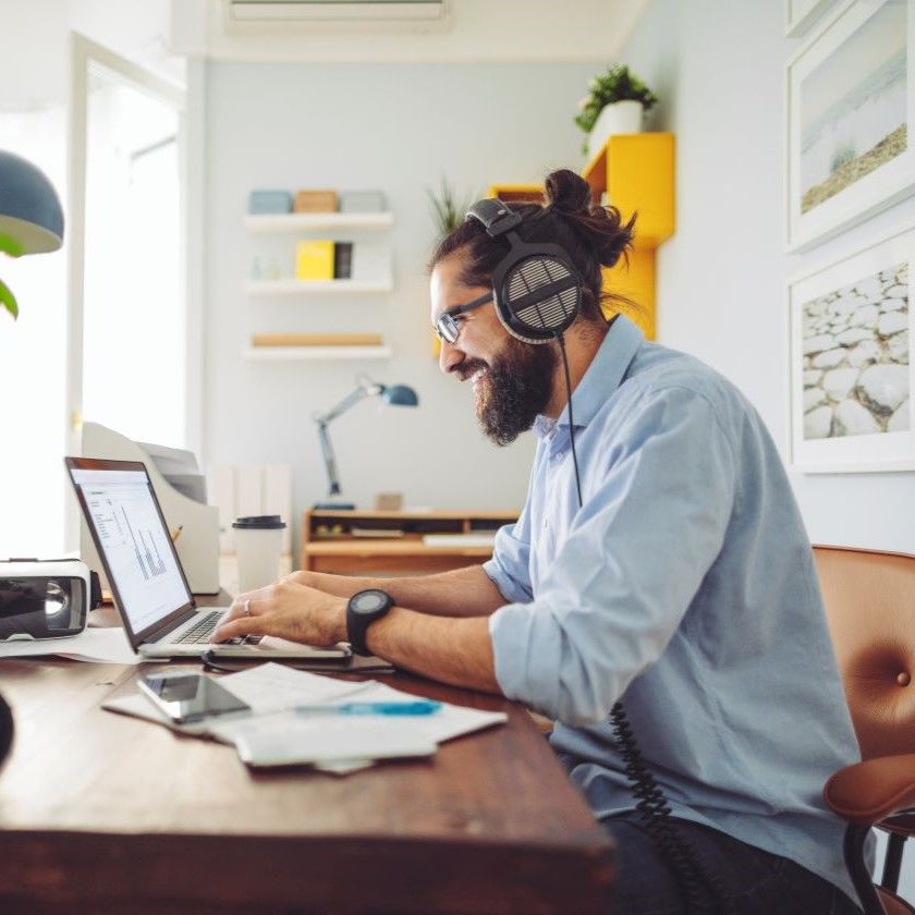 A person sits at their home working station while using their video review tool and smiling.