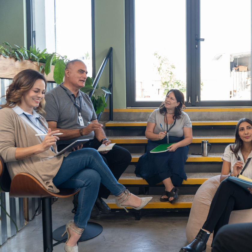 Team sitting together discussing ideas and taking notes, representing collaboration and brainstorming sessions.