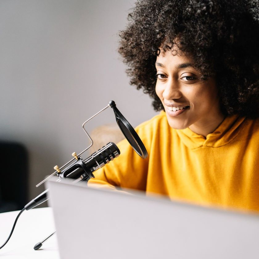 A remote worker participates in a hybrid meeting, using a laptop and microphone.