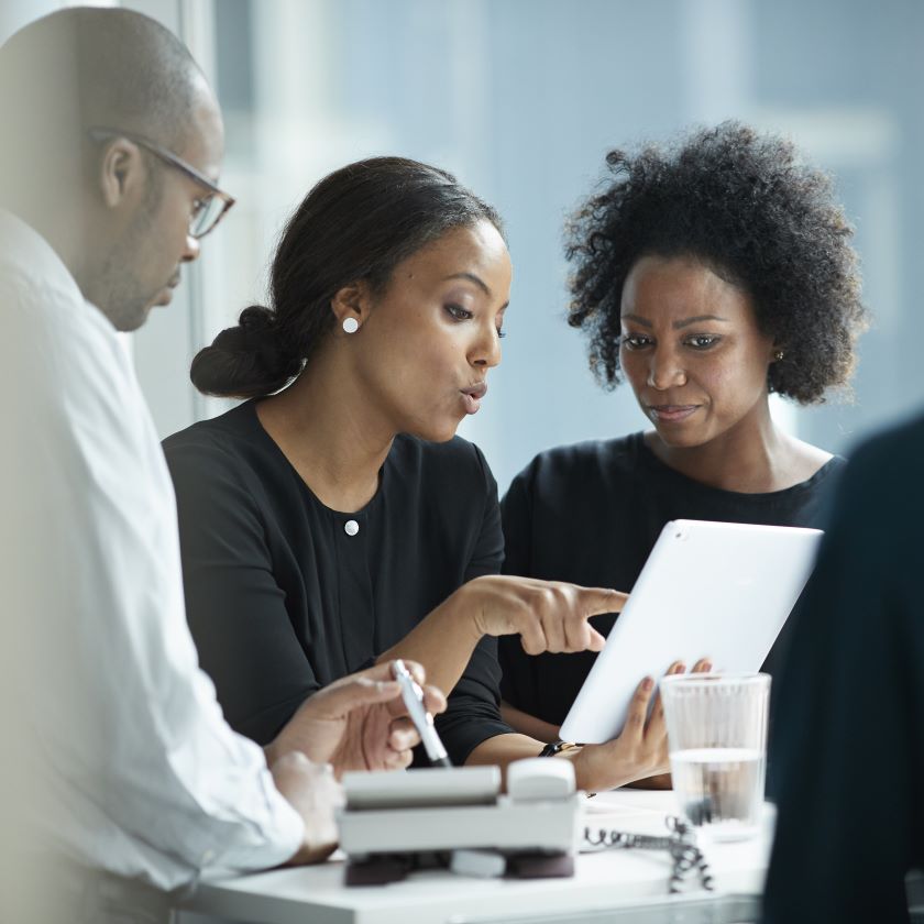 A team discusses a project while viewing their single source of truth on a tablet.