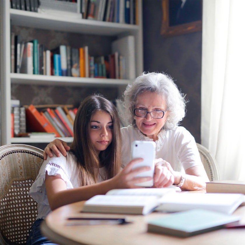 A teenager shows their mobile phone to their grandparent.