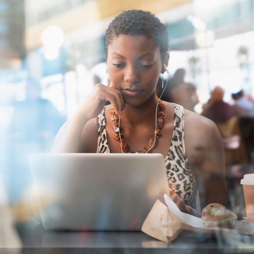 Person using laptop at cafe, focused on screen, representing concept of data security and remote work context.
