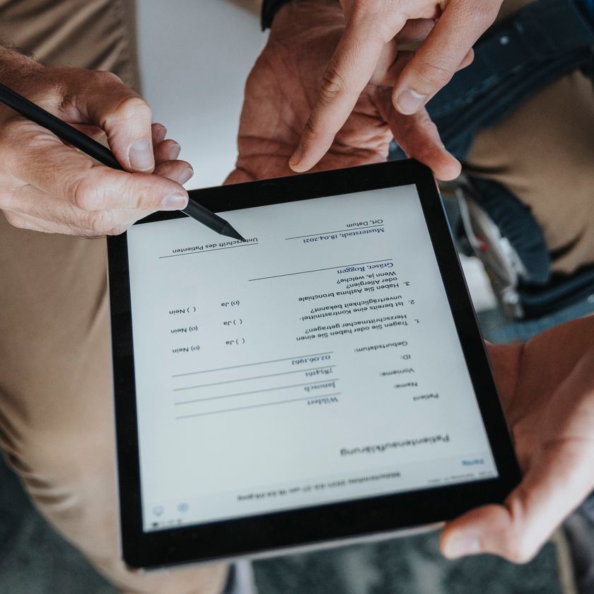 Two workers collaborating on a tablet using a stylus.