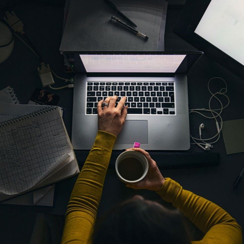 A person managing sensitive work on laptop surrounded by notes, illustrating secure data handling in a personal workspace.
