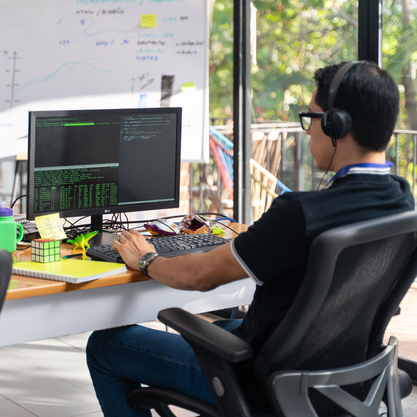 A person with headphones on at their desk works on some code.