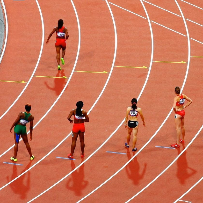 Relay runners stand on a starting grid in preparation for a race.